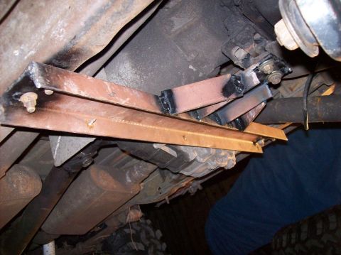 1986 Ford Bronco - Custom fabricated brackets are welded to the vehicle's frame, with visible exhaust and driveshaft components.