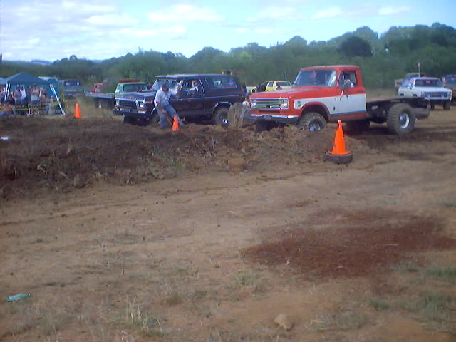 1976 Ford F-100 chassis stuck in mud, front 3/4 view, red and white cab
