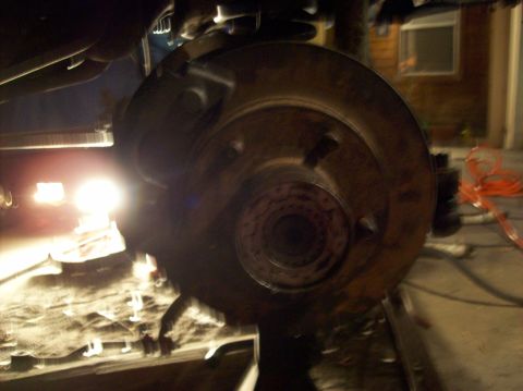 1986 Ford Bronco - This image shows a close-up view of a vehicle's brake rotor and suspension system, illuminated by a bright light.