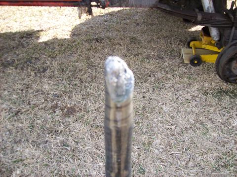 1986 Ford Bronco - A close-up view of a vehicle's suspension component, with a yellow jack and part of the frame in the background.