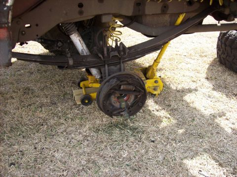 1986 Ford Bronco - Rear axle and suspension components of a vehicle undergoing maintenance, with a jack supporting the axle.