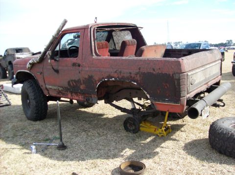 1986 Ford Bronco - This heavily rusted vehicle is missing its wheels and appears to be undergoing repairs or is being dismantled.