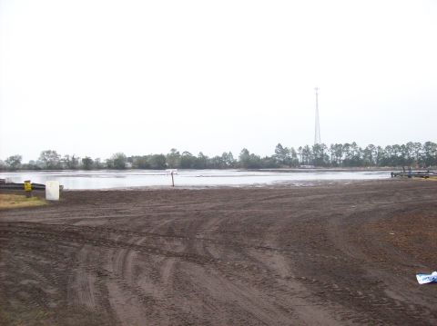 1986 Ford Bronco - A wide view of a muddy landscape adjacent to a calm body of water under an overcast sky.