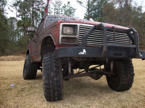 1986 Ford Bronco - This heavily modified Ford Bronco sits on a grassy field, ready for off-road adventures.