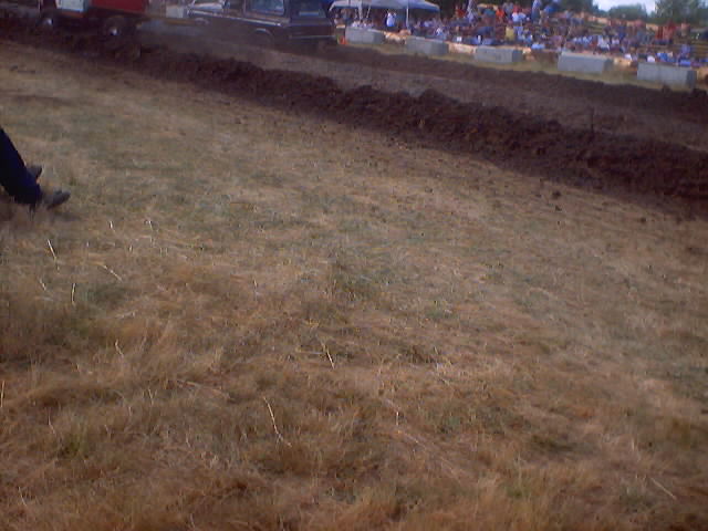 Trucks in a mud drag race with spectators in the background