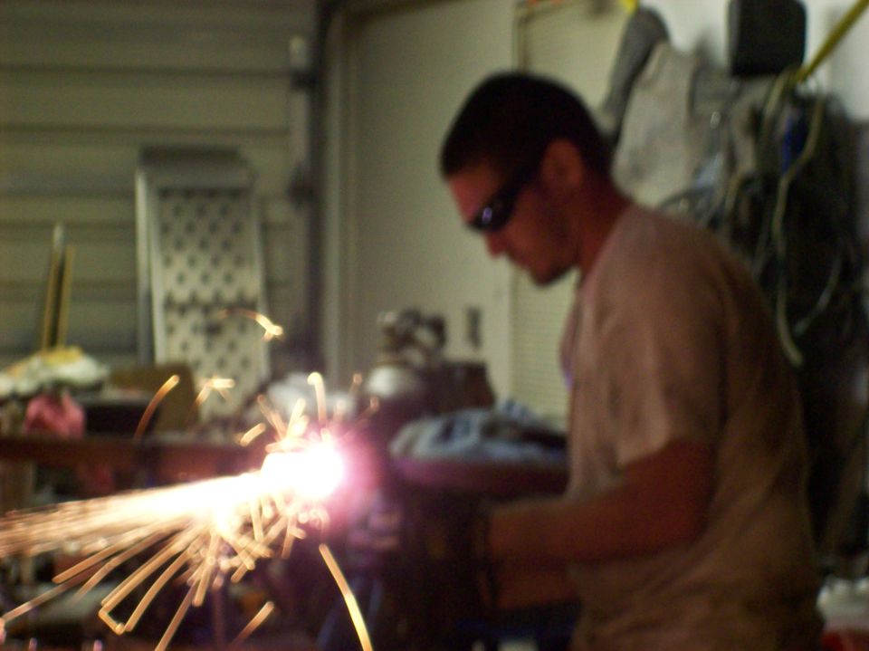 Welding sparks flying in a workshop with a man in sunglasses