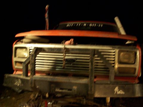 1986 Ford Bronco - Front view of a red truck with a prominent bull bar and custom text on the windshield.