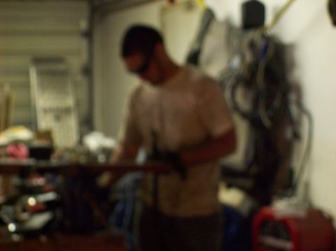 1986 Ford Bronco - Garage scene with a person focused on working with engine parts.