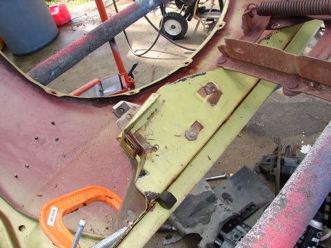 1973 Ford Ranchero - Disassembly shot of a stripped car body on a concrete driveway, showing surface-rusted floor and firewall panels in faded pale yellow-green…