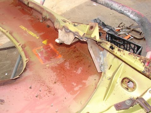 1973 Ford Ranchero - Underside of a removed pale-yellow front fender/inner-structure panel laid on concrete, showing red-oxide primer, surface rust, weld-on bra…