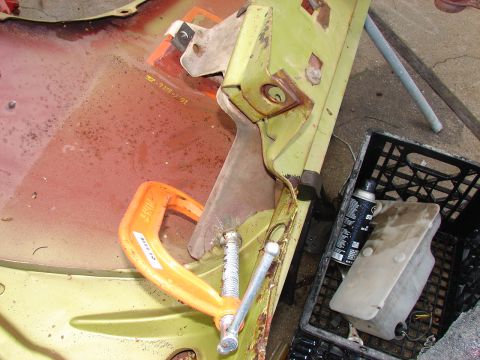 1973 Ford Ranchero - Body repair in progress on a driveway: a lime green outer panel with pink primer showing through is clamped to a rusty steel bracket using…