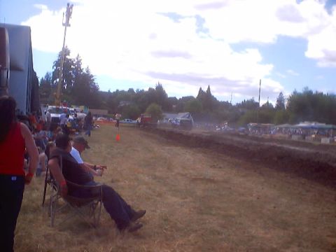 1976 Ford F-100 - Spectators watch a mud drag race event on a sunny day.