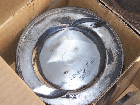 1995 Ford Bronco - A single piston sits inside a cardboard box, showing some wear and identifying marks.