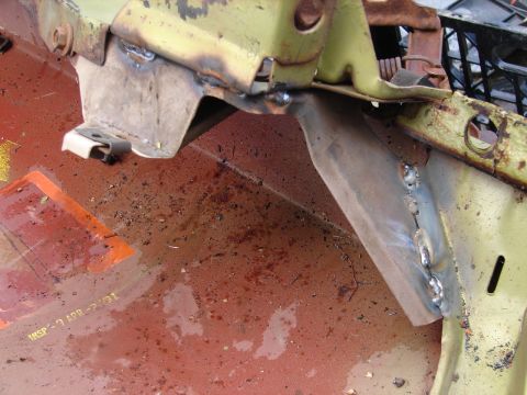 1973 Ford Ranchero - Close-up of bodywork on a partially disassembled vehicle, showing a red-oxide primered inner panel with surface rust and debris meeting a p…