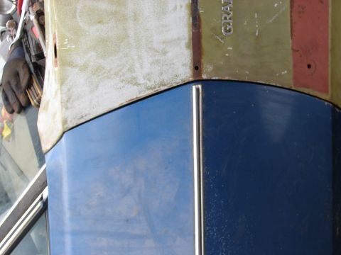 1973 Ford Ranchero - A close-up view of a blue car's hood and a tan panel above, revealing partial text that reads 'GRAN'.