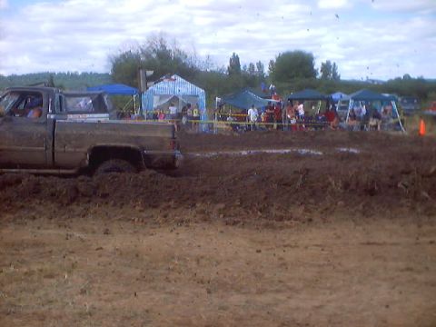 1976 Ford F-100 - A pickup truck is stuck in the mud at a muddy event, with spectators watching in the background.