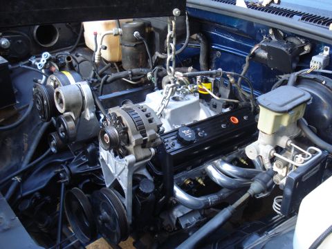 1984 Jeep J-10 - The engine bay of a blue Chevrolet pickup truck, likely from the mid-1990s, is visible with the engine partially disassembled.
