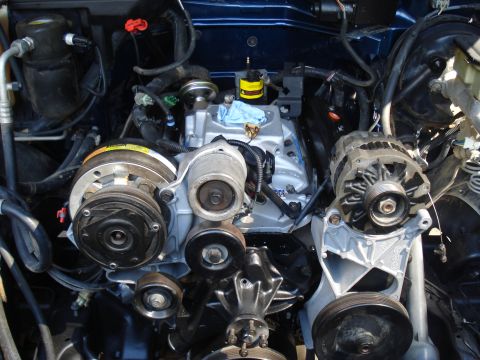 1984 Jeep J-10 - Close-up view of a vehicle's engine bay, highlighting the V-belt system, alternator, and air conditioning compressor.