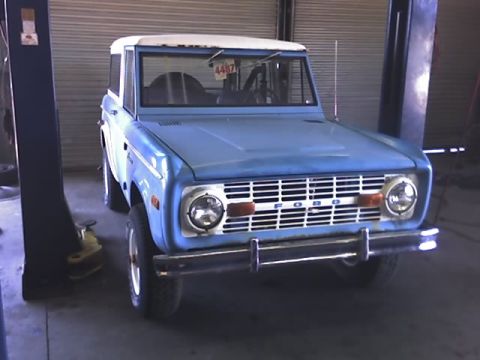 1996 Ford Bronco - A blue first-generation Ford Bronco is parked on a vehicle lift inside a garage.