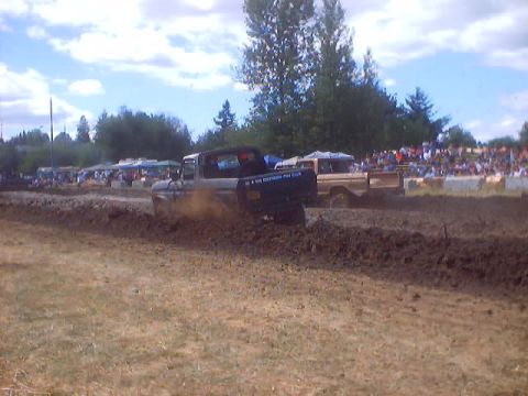 1976 Ford F-100 - A 1976 Ford F-100 competes in a mud drag race, kicking up dirt as it powers through the track.