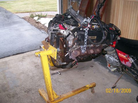 1995 Mercury Grand Marquis - V-engine mounted on a yellow engine stand in a garage doorway, with a Honda dirt bike beside it, dated 02-18-2009.