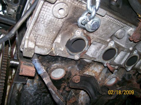 1995 Mercury Grand Marquis - Engine block with exhaust ports visible, a chain is attached to a bolt on the top.