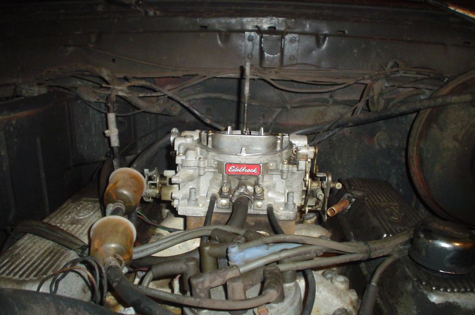 Close-up of an engine bay showing an Edelbrock carburetor and fuel filters