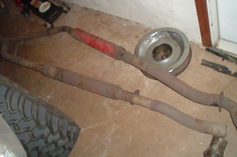 1979 Ford Bronco - Exhaust pipes and a hubcap are visible on the floor, next to a tire and a jack.