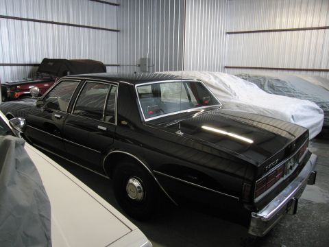 1991 Ford LTD Crown Victoria - Photograph of a black Chevrolet Caprice sedan in a storage building, not a technical document.