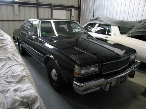 1991 Ford LTD Crown Victoria - Photograph of a black Chevrolet Caprice sedan in storage, not a technical document.