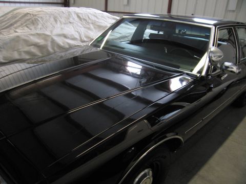 1991 Ford LTD Crown Victoria - Photograph of a black sedan's hood and windshield in a storage building, not a technical document.