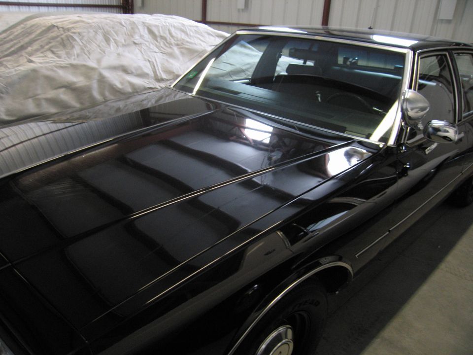 Close view of a black sedan's hood and windshield in storage