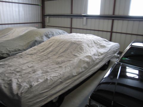 1991 Ford LTD Crown Victoria - Photograph of car-covered vehicles next to a black sedan in storage, not a technical document.