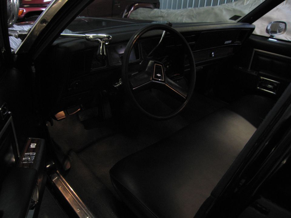 Dark interior of a classic sedan showing steering wheel and bench seat