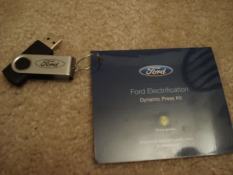 1998 Ford Taurus - Ford USB drive and press kit document on a carpeted surface.
