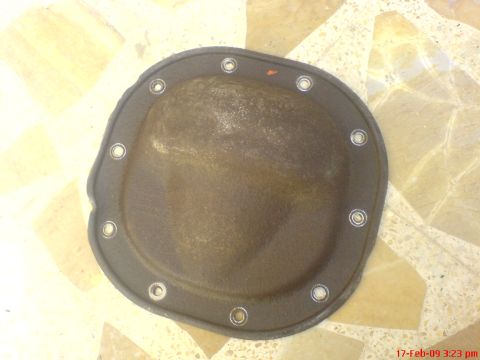 1992 Ford Crown Victoria - A dark brown differential cover with a black gasket and silver bolts is shown from a top-down perspective. The cover is resting on a tiled…