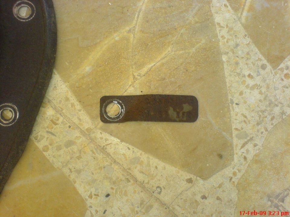 Close-up of a metal tag on a speckled floor.