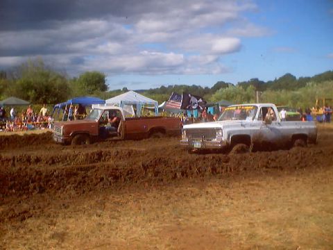 1976 Ford F-100 - Pickup trucks compete in a mud bog event, with one truck appearing to be from the 1970s.