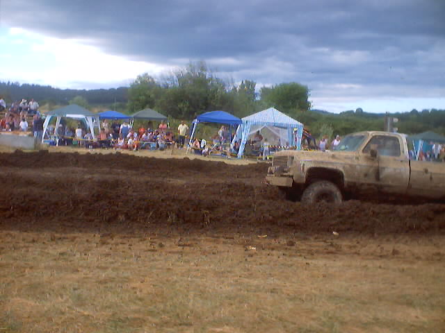 Mud-covered pickup truck stuck in mud at a drag race event