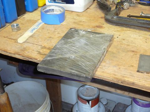 1991 Ford Bronco - Metal parts and tools are laid out on a wooden workbench for assembly or repair.