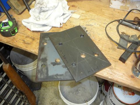 1991 Ford Bronco - Two metal plates, one with scribe lines and multiple holes, rest on a wooden workbench.