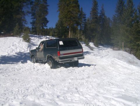 1990 Ford Bronco - Ford Bronco navigates a snow-covered trail in a wooded area.