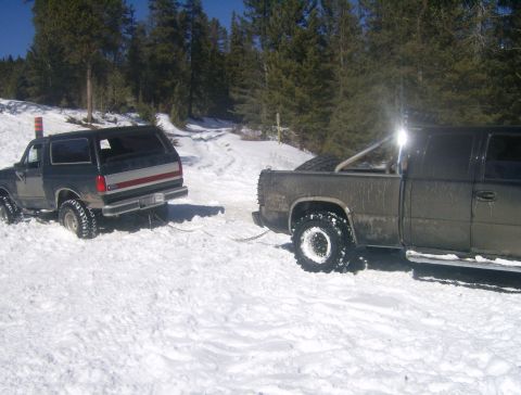 1990 Ford Bronco - A Ford Bronco is being towed out of the snow by a pickup truck on a winter day.