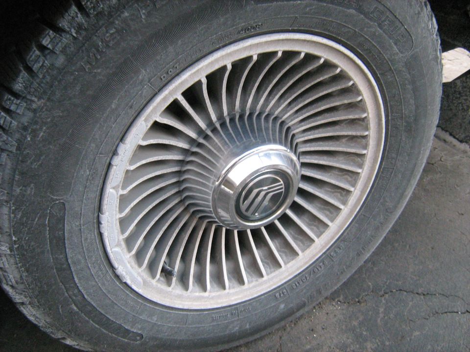 Close-up of a Mercury wheel with a badge in the center. Tire has some text on it