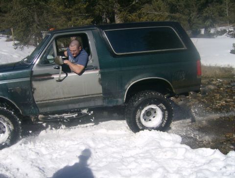 1990 Ford Bronco - Man drives a 1990 Ford Bronco through a snowy, off-road area.
