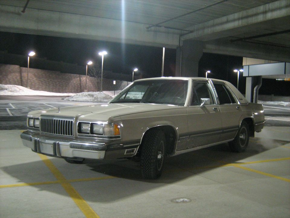 Tan sedan with a chrome grille and bumper, parked in a garage at night