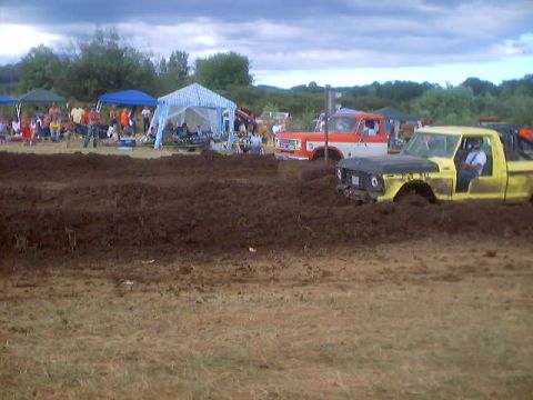 1976 Ford F-100 - Two trucks are stuck in the mud during a drag race event.