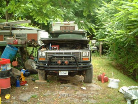 1982 Ford Bronco - Front view of a 1980 Ford Bronco, hood open, parked outdoors with various items around it.