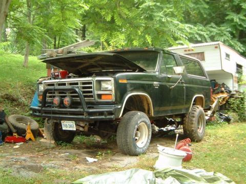 1982 Ford Bronco - This Ford Bronco appears to be undergoing some maintenance with its hood open and various items scattered around.