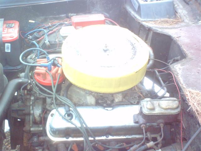 Engine bay with a yellow air cleaner, red distributor cap, and two batteries